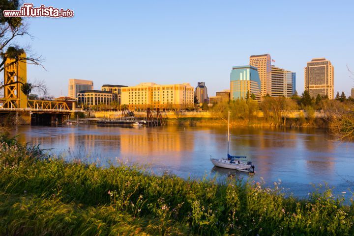 Immagine Sacramento al tramonto, California - Una bella immagine della città fotografata con i riflessi color arancio al calar del sole: le acque navigabili del fiume hanno sullo sfondo palazzi moderni e fabbricati antichi © Andrew Zarivny / Shutterstock.com