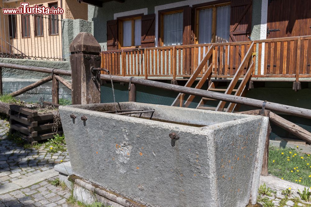 Immagine Scorcio del borgo di Claviere, provincia di Torino, Piemonte: una fontana in legno con vasca in pietra.