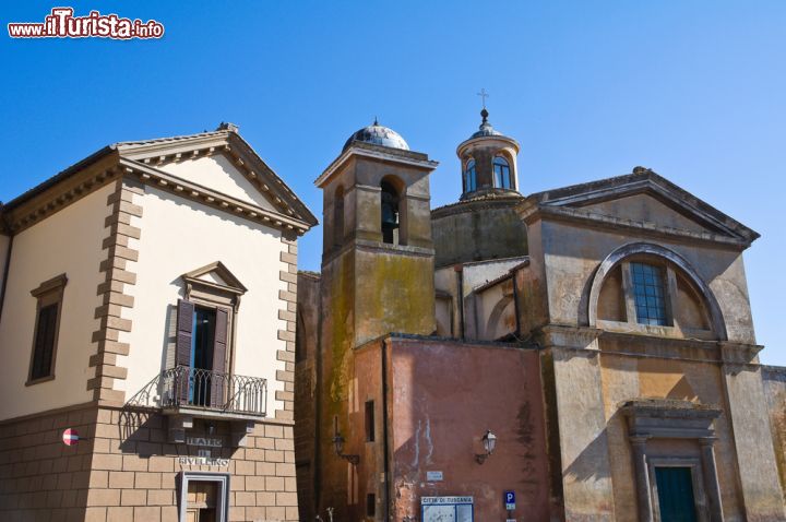 Immagine Scorcio della chiesa dei Santi Martiri a Tuscania, Lazio. La facciata ottocentesca si presenta con un ampio arco sorretto da due robusti piedritti e in alto un finestrone.