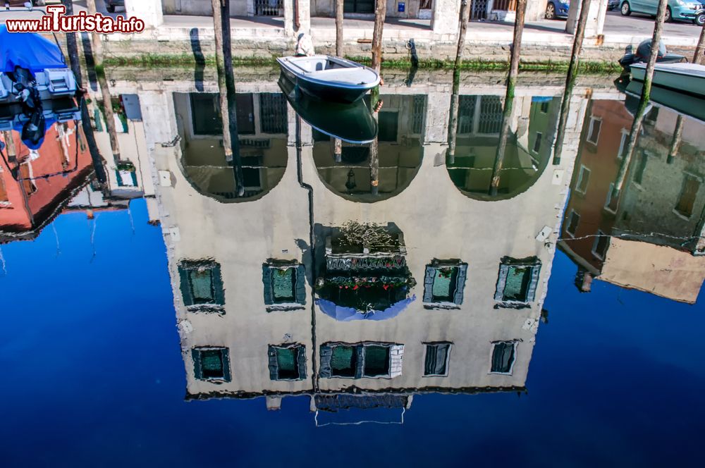 Immagine Scorcio fotografico di una strada nei pressi del canale con riflessi sull'acqua a Chioggia, Veneto, Italia.