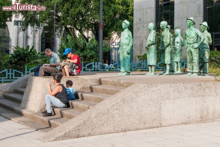 Immagine Persone sedute di fronte alle sculture di San José, Costa Rica. Ogni giorno residenti e turisti si siedono per un momento di relax o per una fotografia ricordo davanti a queste sculture in bronzo della capitale - © De Jongh Photography / Shutterstock.com