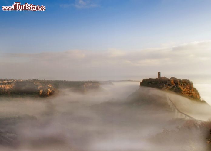 Immagine Nebbia a Civita di Bagnoregio, Lazio: il borgo si erge quasi surreale da una coltre di foschia lasciando intravedere il campanile in stile romanico che affianca la chiesa - © ER_09 / Shutterstock.com