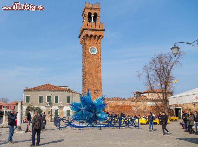 Immagine La Torre Civica di Murano e la Cometa di Vetro - la Torre Civica di Murano, sita nella splendida piazza Campo Santo Stefano, fu costruita in stile medievale alla fine del XIX secolo, sulle fondamenta del campanile della Pieve di Santo Stefano. Proprio di fronte a questo nel monumento, si trova un'altro simbolo di Murano, una bellissima opera d'arte intitolata "Cometa di Vetro". La Cometa, opera dell'artista veneziano Simone Cenedese, è l'emblema della celebre arte della lavorazione del vetro di Murano. - © mikecphoto / Shutterstock.com