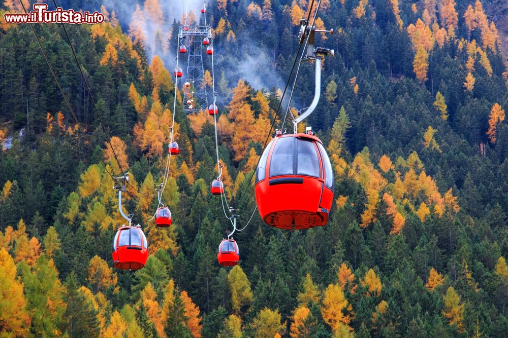 Immagine Skilift per l'Alpe di Siusi dal centro sciistico di Ortisei, Trentino Alto Adige. Sullo sfondo, montagne con foliage autunnale.