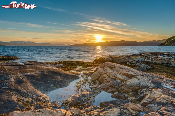 Immagine Durante l'estate in Norvegia il sole non tramonta mai a nord del Circolo Artico e per qualche mese è visibile 24 ore al giorno. Il fenomeno del "sole a mezzanotte" è causato dall'inclinazione dell'asse terrestre, una linea immaginaria che corre da un polo all'altro su cui ruota la terra. Muovendosi così, l'inclinazione dell'asse fa in modo che il Polo Nord sia esposto verso il sole e lontano da esso d'inverno. Da questo deriva la luce continua durante l'estate: 24 ore di raggi solari che donano a flora e fauna lungo la costa una grande carica di energia - © Anibal Trejo / Shutterstock.com