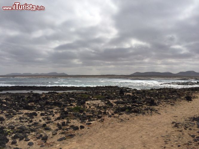 Immagine La spiaggia di El Cotillo verso il Faro, Fuerteventura (Spagna) - Quando si arriva qui ci si trova di fronte alla scritta "Vergine de Buen Viaje" che tradotto significa "Vergine di Buon Viaggio". Questo detto, dipinto sulla scogliera, apre le porte di questo villaggio di pescatori. Sublimi le spiagge e molto tranquille, nel circondario sono dotate di deliziosi bar e ristoranti da cui poter ammirare il panorama nonché negozi tipici.