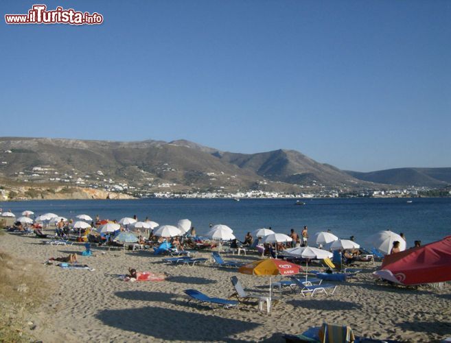 Immagine Turisti sulla spiaggia di Marchello a Paros, Cicladi. Nei mesi estivi le spiagge greche sono meta di viaggiatori provenienti da tutto il mondo. Quella di Marchello o Martselo è una lunga spiaggia di sabbia chiara, ideale per famiglie con bambini, che si trova nella baia di Parikia e si affaccia sulla capitale. Nelle vicinanze si trova uno dei tanti campeggi dell'isola.