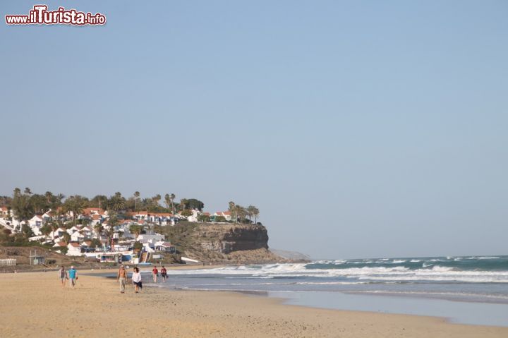 Immagine Litorale di Morro Jable, Fuerteventura (Spagna) - Ben quattro chilometri di litorale compongono la realtà della spiaggia situata a sud di Fuerteventura, ossia Morro Jable. Qui oltre ad una bellissima scenografia composta da un paesaggio marino stupendo, si può anche trovare nella parte più cittadina (come si vede dal fondo dell'immagine) uno scenario fatto di negozi, bar con vista mare e comodità di ogni tipo, per consentire ad ogni turista di non farsi mancare nulla.