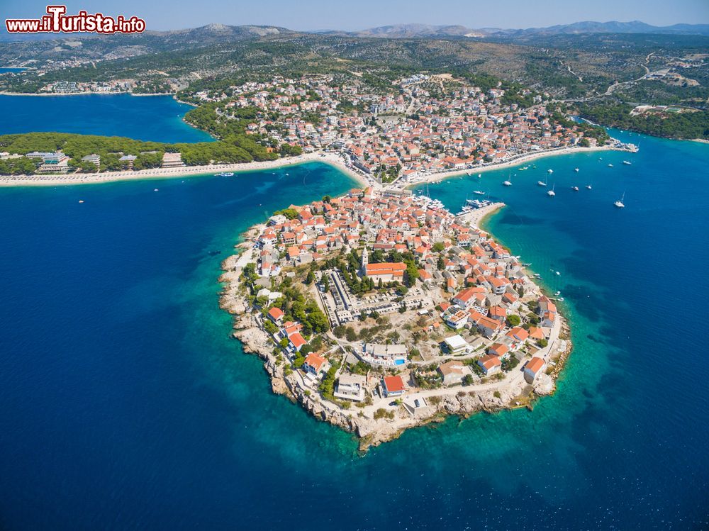 Immagine La splendida città medievale di Primosten, Croazia, fotografata dall'alto. Estesa fra le baie di Raduca e di Primosten, questa località è suddivisa su due penisole gemelle protese verso il mare.