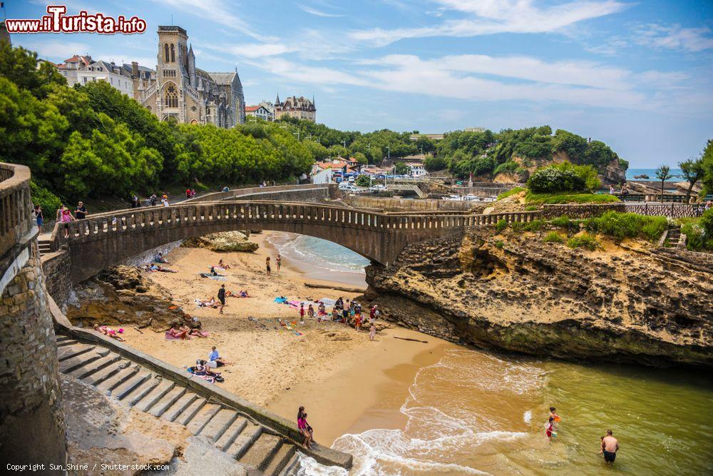 Immagine La splendida veduta di una spiaggetta cittadina a Biarritz con ponte e scalinata, Francia. Sullo sfondo, la chiesa di Santa Eugenia, costruita nel 1898 nel luogo in cui si trovava la cappella di Nostra Signora della Misericordia - © Sun_Shine / Shutterstock.com