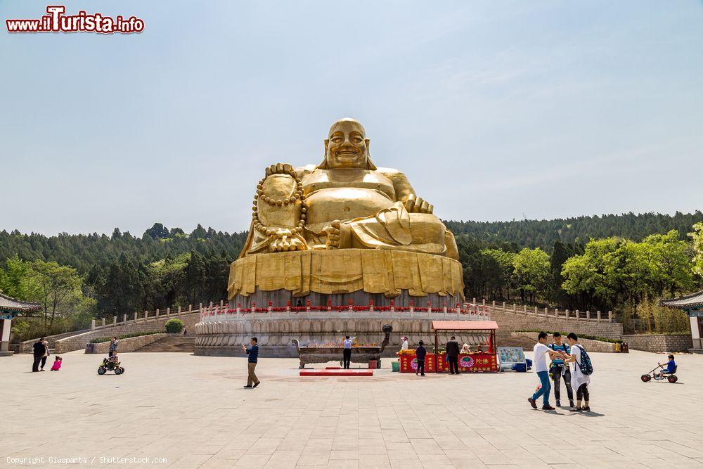 Immagine Turisti di fronte alla grande statua d'oro del Buddha a Qianfo Shan, Jinan, Cina. Questa piccola collina a sud di Jinan ospita templi, grotte, padiglioni, terrazze, torri e l'imponente statua dorata del Buddha. E' chiamata anche Thousand-Buddha Hill - © Giusparta / Shutterstock.com