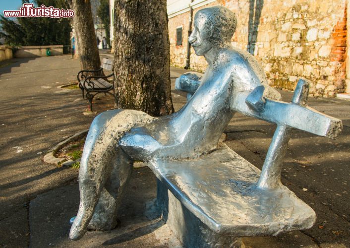 Immagine Statua del poeta Antun Gustav Matos a Zagabria, Croazia. Passeggiando nella città alta si possono ammirare alcuni monumenti fra cui questa singolare opera scultorea che ritrae il poeta Matos seduto su una panchina. Ai turisti piace molto fotografarsi con l'artista accanto - © iascic / Shutterstock.com