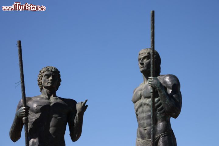 Immagine Ayos e Guize, le due statue di bronzo a Fuerteventura, Isole Canarie, Spagna - Quando Guize strinse un'alleanza con Ayos per scacciare i conquistadores che avevano invaso i loro territori, correva l'anno 1405 circa. Da allora, i due vennero visti come i "giganti" che provarono a combattere per la difesa della loro terra e, da lì, deriva la loro altezza decisamente imponente. Misurano infatti 4 metri di altezza l'una e la loro aria magnetica attira moltissimi turisti che intendono non solo conoscere la storia di Fuerteventura ma ammirarne anche l'arte e la cultura.