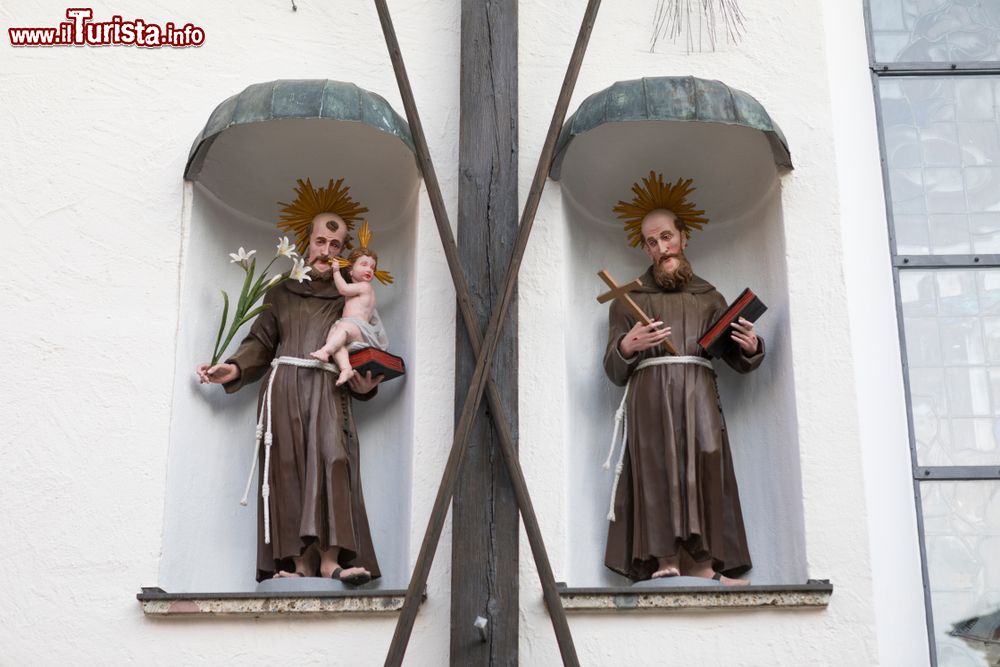 Immagine Statuette di monaci nella nicchia di un edificio religioso a Altotting, Germania. Quello di sinistra tiene in braccio il Bambino Gesù mentre l'altro una copia della Bibbia.