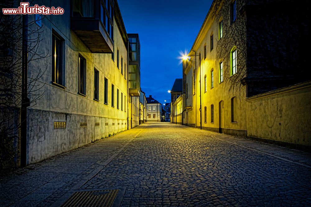 Immagine Una strada con pavimentazione a ciottoli nel centro storico di Lund, Svezia, illuminata di notte.