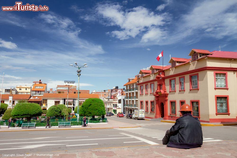 Immagine Street view a Puno, Perù: un lavoratore con elmetto seduto di fronte alla Plaza de Armas in un caldo pomeriggio estivo - © Simon Mayer / Shutterstock.com