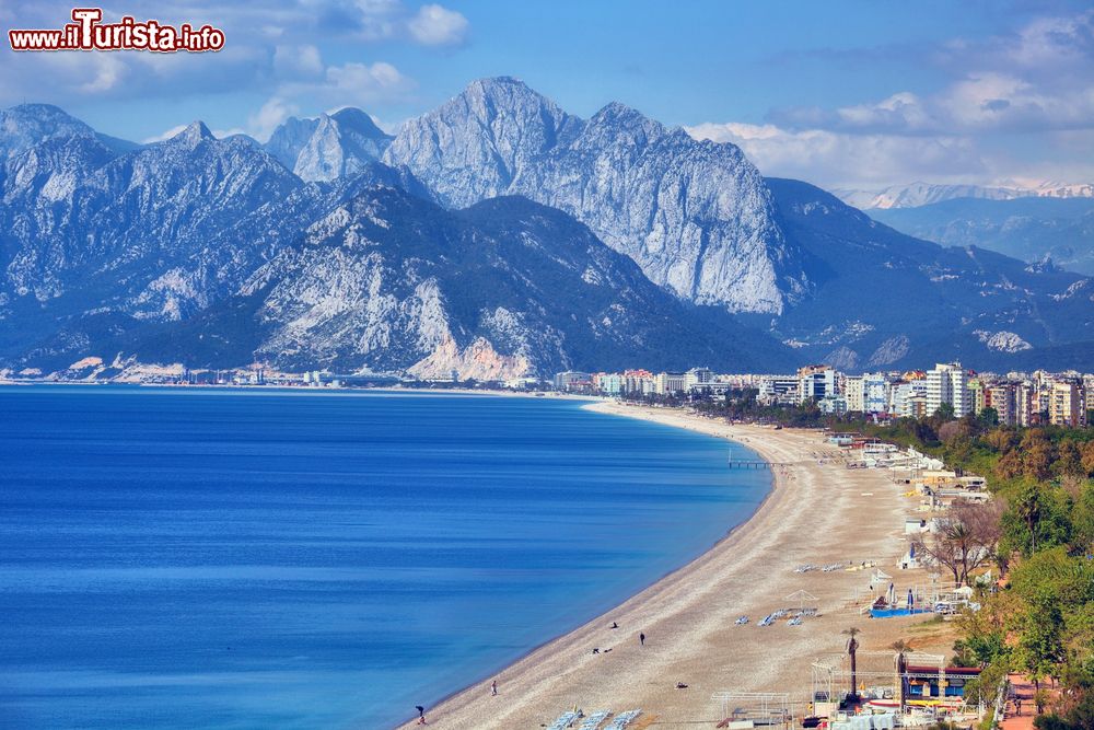 Immagine Una suggestiva veduta della spiaggia di Konyaalti, Antalya, Turchia. Si trova sul lato occidentale della città e si estende per circa 7 chilometri a ovest di Antalya. Grazie al mare cristallino, la sabbia dorata e i piccoli ciottoli, è una delle località più frequentate dai turisti e dai residenti.