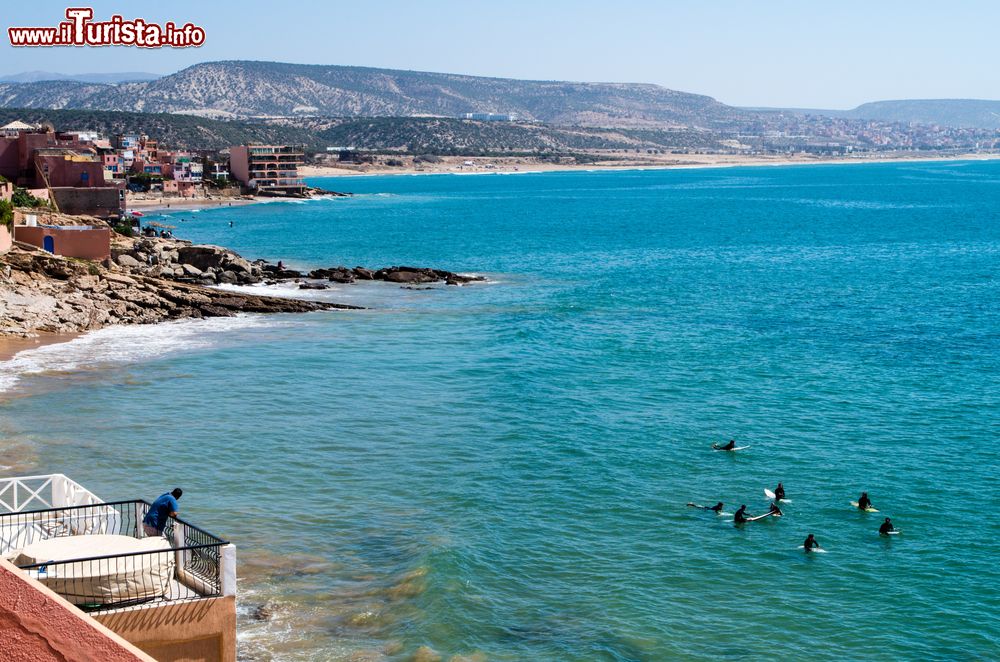 Immagine Surfers a Taghazout in attesa dell'onda perfetta, Marocco. Le correnti dell'oceano mitigano il caldo di questo territorio mantenendo in estate una temperatura massima di 26/27° C e di 20° C circa in inverno. Nei mesi più freddi però è necessaria una muta in neoprene per avventurarsi nelle acque che possono avere una temperatura di soli 17° C.