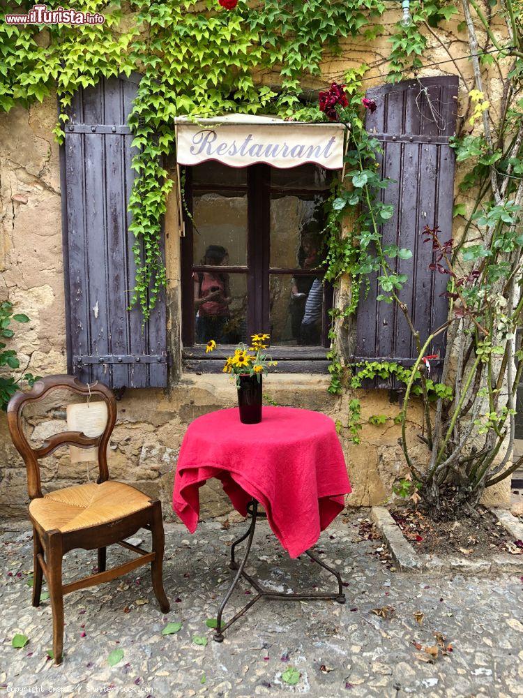 Immagine Tavolino e sedia di fronte alla finestra di un ristorante nel centro di Monpazier, Francia - © Cmspic / Shutterstock.com