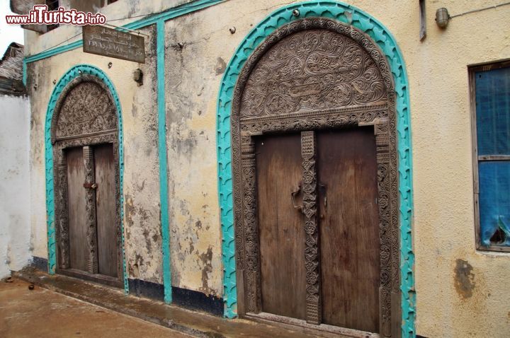 Immagine Una tipica porta in legno a Lamu, Kenya - molti edifici di Lamu, la più grande città dell'omonima isola kenyota, mostrano ancora le tracce della dominazione dell'Oman sull'isola. Questo periodo può essere considerato una vera e propria "golden age" nella storia di Lamu, in quanto l'influenza del prestigioso sultanato rese la città, e l'isola, luoghi di poesia, arte e artigianato. Un antico splendore che, fortunatamente, non si è ancora perso. - © Przemyslaw Skibinski / Shutterstock.com