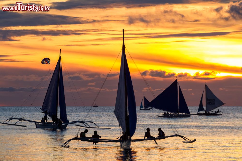 Immagine Il tramonto con le tipiche imbarcazioni delle Filippine nel mare che lambisce Boracay. L'isola è raggiungibile solo via mare, perché non esistono aeroporti.