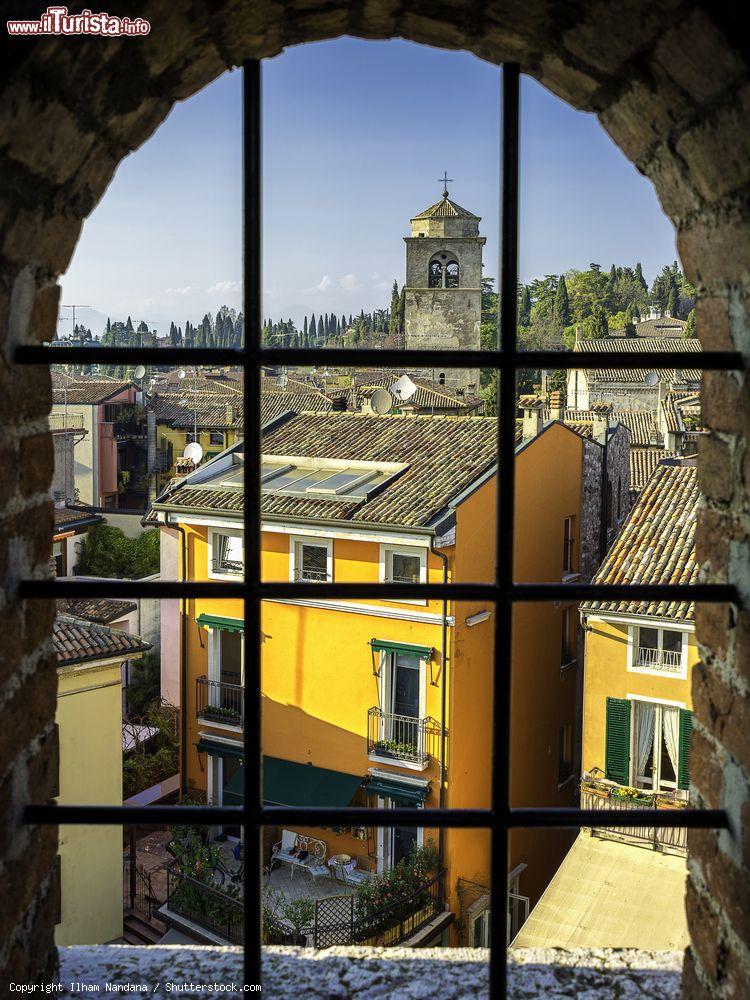 Immagine Tramonto a Sirmione visto da dietro la finestra di un antico palazzo, Lombardia.  Siamo in una delle cittadine affacciate sul Lago di Garda più frequentate dai turisti - © Ilham Nandana / Shutterstock.com