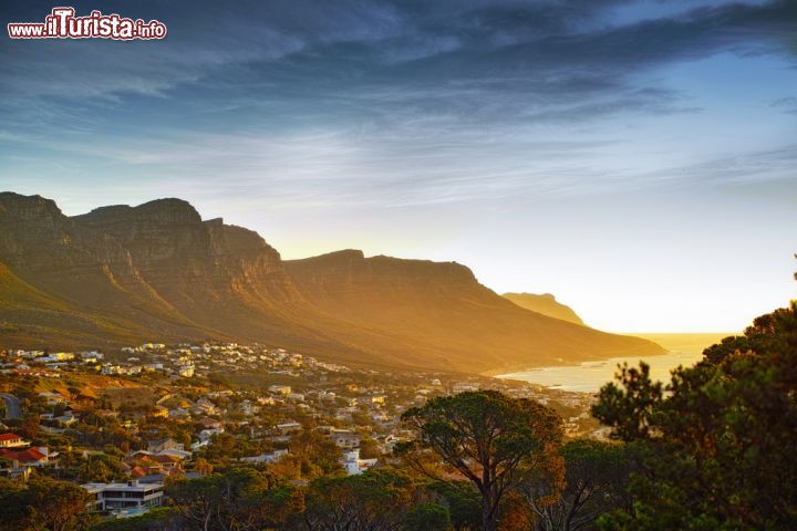 Immagine Tramonto e vista sulla città di Cape Town, Sudafrica - Sembra piccolissima la città del Capo e quella montagna in mezzo, table mountain, sembra grandissima. Quando queste due realtà agli antipodi incontrano la luce del tramonto, lo spettacolo generato è unico. Un cielo superbo si dipinge di tinte calde e va a posarsi in ogni angolo, creando una scenografia senza eguali - © Dhoxax / Shutterstock.com