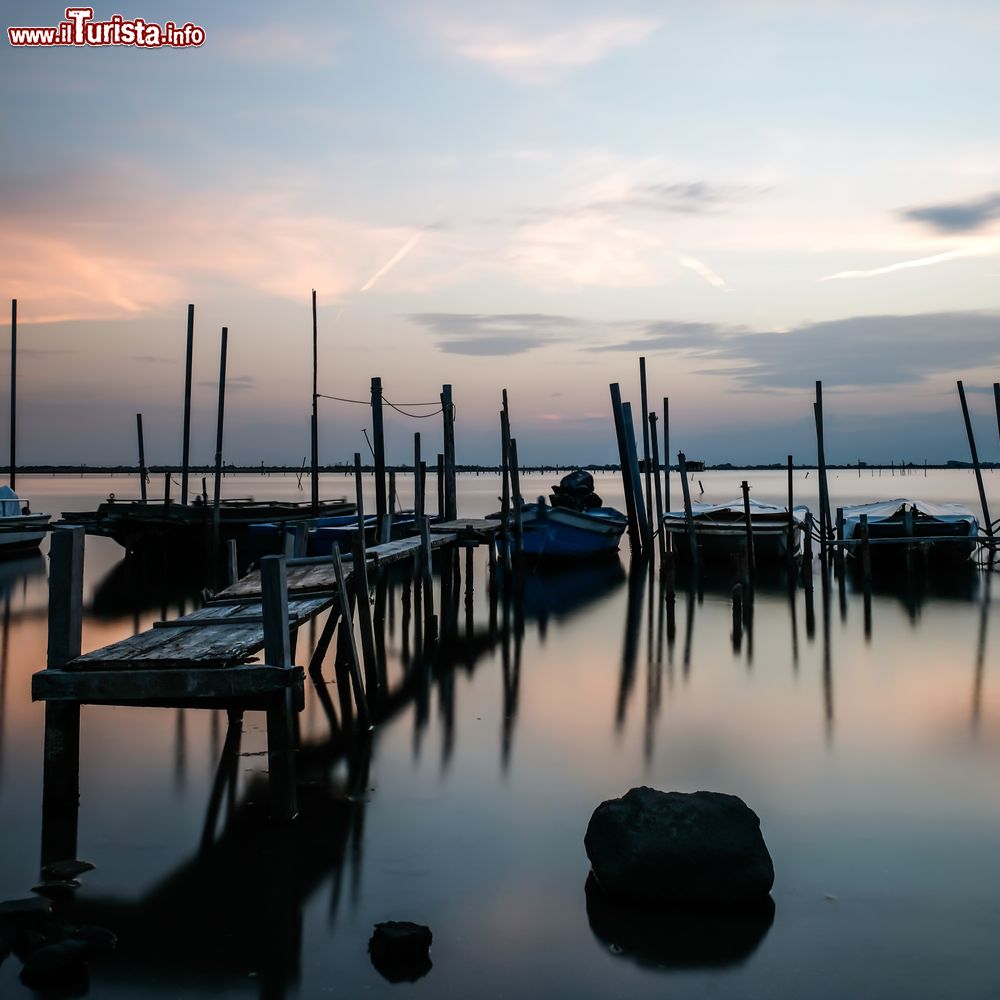 Immagine Tramonto su un molo in legno e sulle barche a Rosolina, Veneto. 