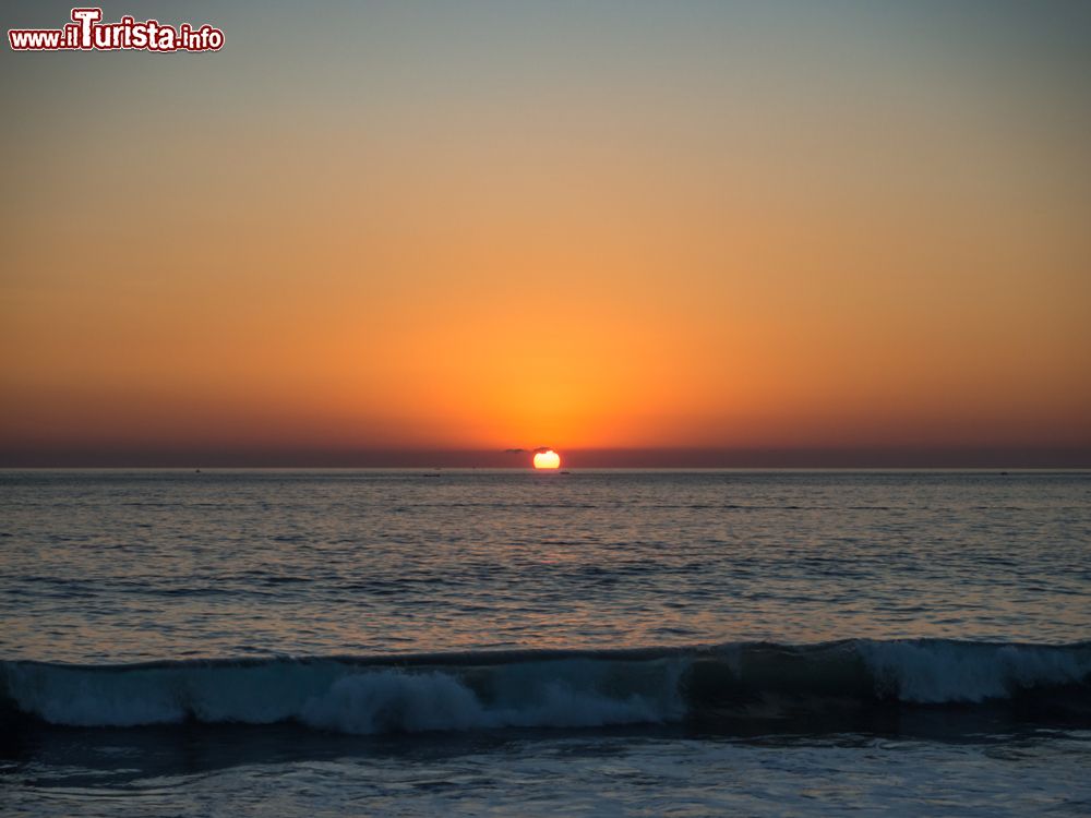 Immagine Tramonto su una spiaggia di Puerto Escondido, Messico, con le sfumature del cielo riflesse nell'acqua dell'oceano.