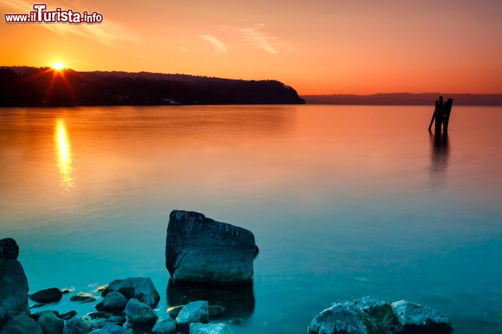 Immagine Tramonto sul lago di Bracciano a Anguillara Sabazia, provincia di Roma, Lazio. Riflessi arancioni sulle acque azzurre del bacino lacustre rendono ancora più suggestiva l'atmosfera del paesaggio.