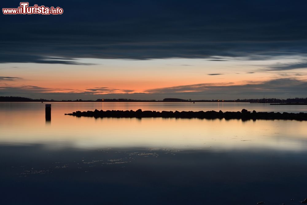 Immagine Tramonto sul lago Veerse nella regione di Zeeland, Paesi Bassi. Fa parte del delta del Reno, della Mosa e della Schelda; meta di pescatori e di chi pratica il windsurf, la canoa e lo sci nautico, il Veerse Meer è classificato lago dal 1961.