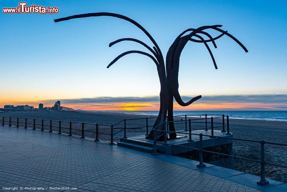 Immagine Tramonto sul lungomare di Ostenda (Belgio) con la skyline della città sullo sfondo. In primo piano, opera d'arte "Onde Danzanti" di Patrick Steen installata nel 2008 - © SL-Photography / Shutterstock.com