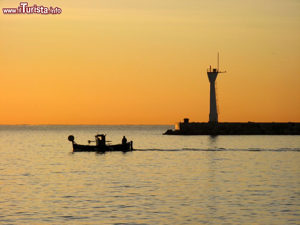 Immagine Tramonto sul porto di La Ciotat, Francia, con una barca in mare e il faro.