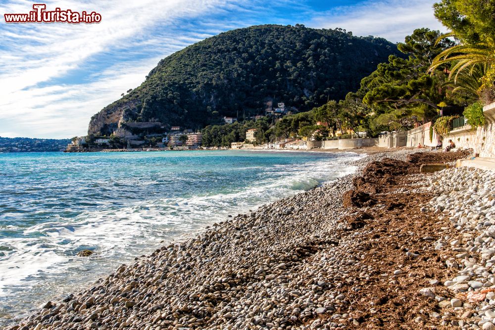 Immagine Un tratto di spiaggia di Eze-sur-Mer (Francia) con le montagne ricoperte di vegetazione sullo sfondo.