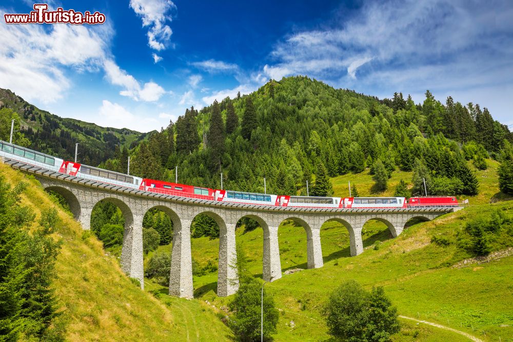 Immagine Il treno Glacier Express mentre attraversa il famoso ponte sul viadotto Landwasser in estate (Svizzera). Questo spettacolare ponte in pietra a sei archi varca la profonda gola in cui scorre il torrente Landwasser nel cantone svizzero dei Grigioni.