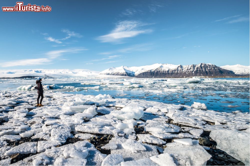 Immagine Una turista sulle rive della Jokulsarlon Glacier Lagoon, il lago sul quale galleggiano gli iceberg che si staccano dal ghiacciaio Breiðamerkurjökull, in Islanda.