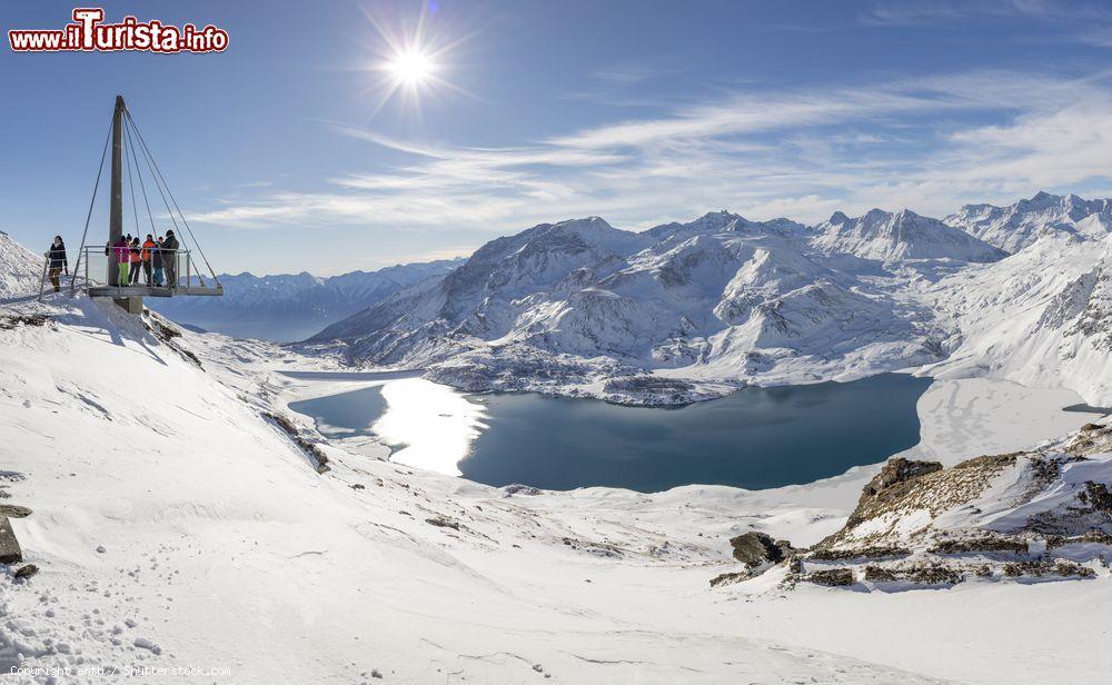 Immagine Turisti ammirano il lago del Moncenisio e le montagne innevate dal belvedere panoramico al Col de la Met, Francia (Val Cenis) - © antb / Shutterstock.com