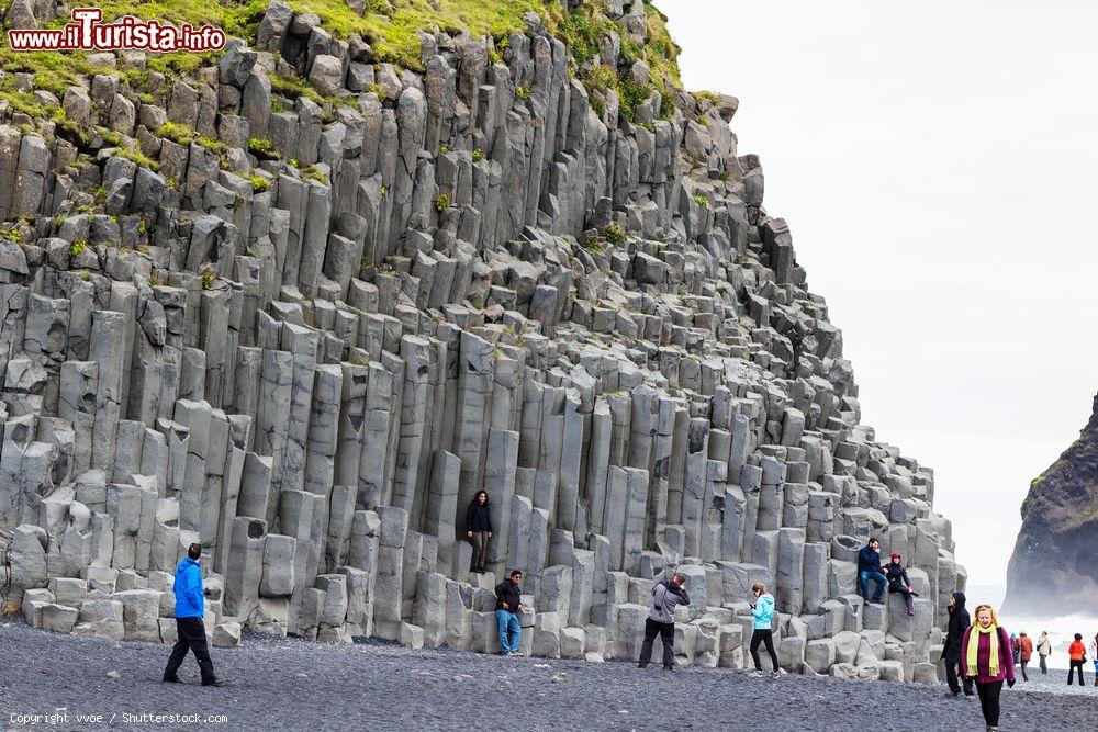 Immagine Turisti vicino al monte Reynisfjall sulla spiaggia lavica di Reynisfjara, Vik i Myrdal, Islanda. Questa montagna si eleva per 340 metri e per 5 chilometri in lunghezza. Di particolare interesse sono le sue colonne di basalto - © vvoe / Shutterstock.com