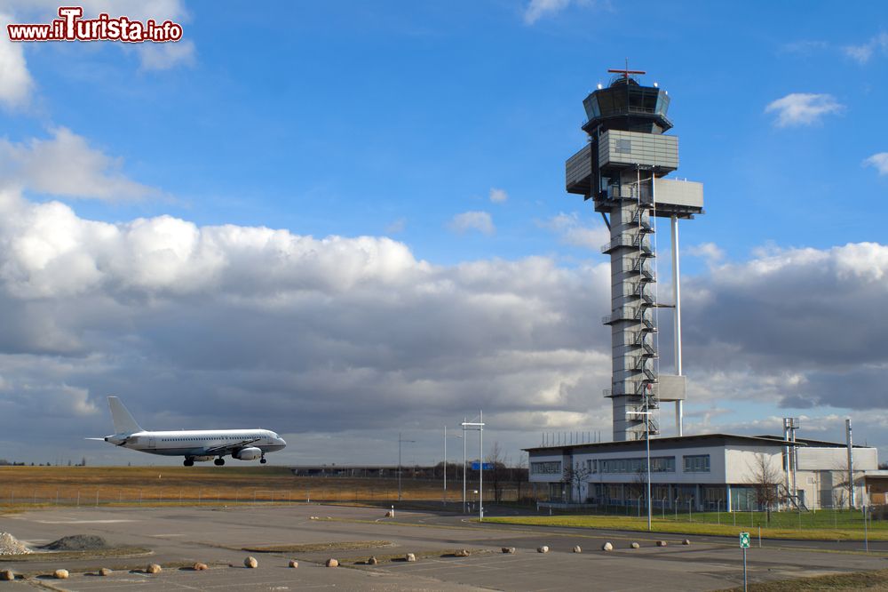 Immagine Un aereo sulla pista di atterraggio dell'aeroporto di Lipsia, Germania, con la torre di controllo in una giornata nuvolosa.