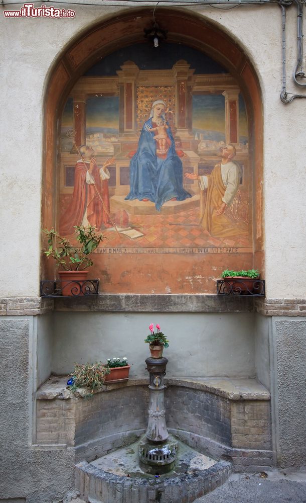 Immagine Un angolo caratteristico di Spello, Umbria. A impreziosire questo Comune situato ai piedi del monte Subasio ci sono decorazioni pittoriche e graziose fontane come quella ritratta in questa nicchia del centro.