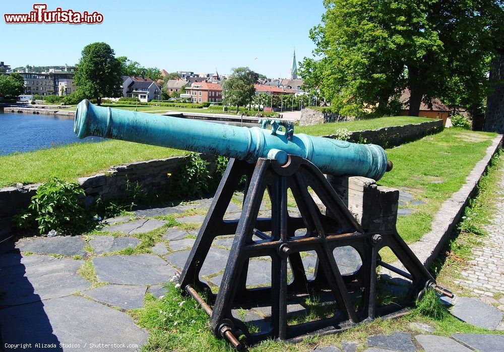 Immagine Un cannone della Christiansholm Fortress a Kristiansand, Norvegia, con il paesaggio cittadino sullo sfondo. Ad impreziosire questa fortificazione tozza e circolare costruita nel 1672 è un bastione chiuso con 8 cannoni di bronzo sigillati  - © Alizada Studios / Shutterstock.com