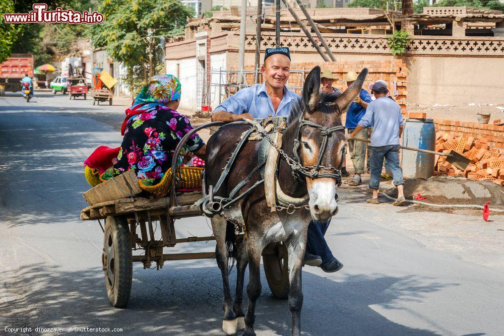 Immagine Un carretto trainato da un asino con un uomo  e una donna in una strada di Turpan, Xinjiang, Cina - © dinozzaver / Shutterstock.com