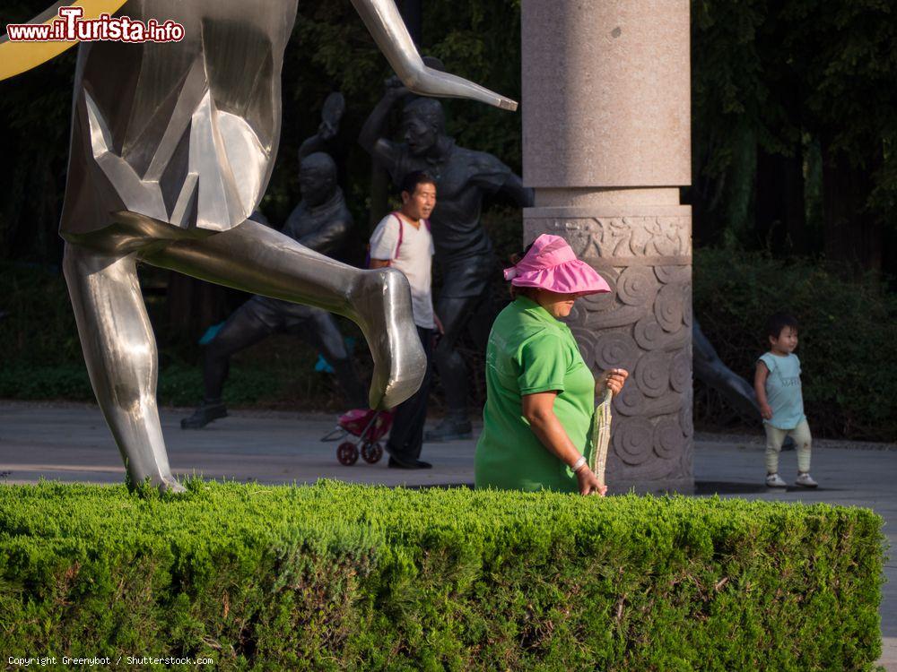 Immagine Un cinese al lavoro con indosso il tradizionale copricapo, qui colorato, all'Olympic Sculptural Culture Park di Qingdao, Cina - © Greenybot / Shutterstock.com