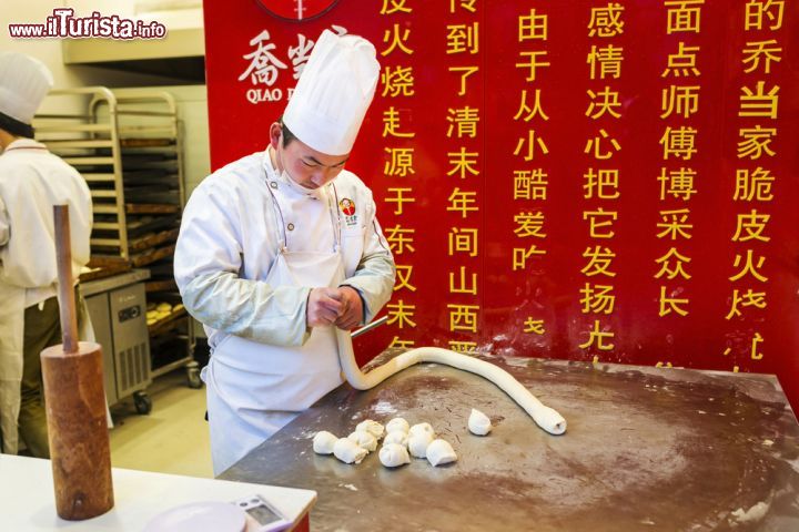 Immagine Un cuoco cinese prepara i tradizionali Huoshao a Nanjing. Considerato uno dei più noti cibi da strada della Cina, è preparato con carne, fegato e intestino di maiale a cui si aggiungono altri ingredienti fra cui salse varie - © aphotostory / Shutterstock.com