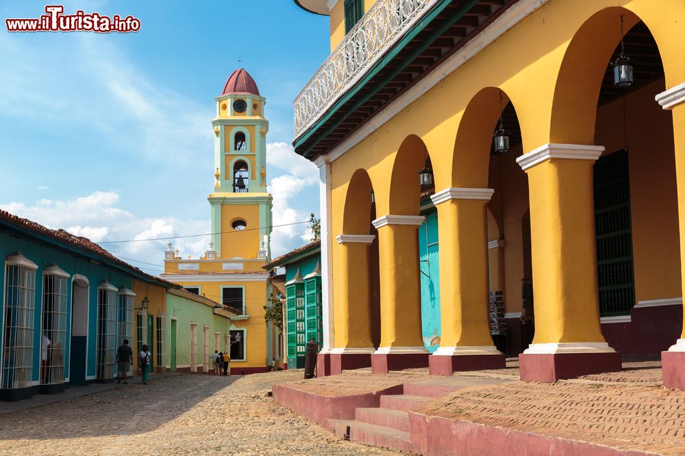 Immagine Un edificio coloniale restaurato e, sullo sfondo, la sagoma della chiesa di San Francisco de Asis a Trinidad, Cuba - © gvictoria / Shutterstock.com