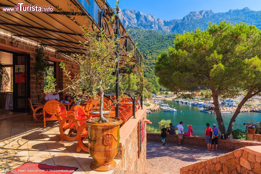 Immagine Un grazioso ristorante nel borgo di Porto, Corsica, in estate. Sullo sfondo, uno scorcio della baia di Porto fra scogliere a strapiombo e paesaggi mozzafiato - © Pawel Kazmierczak / Shutterstock.com