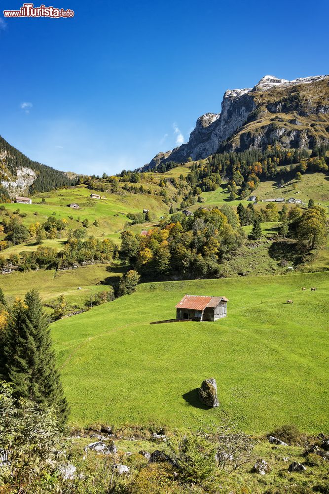 Immagine Un grazioso villaggio di montagna con le cime sullo sfondo, valle di Muotathal, Svizzera.