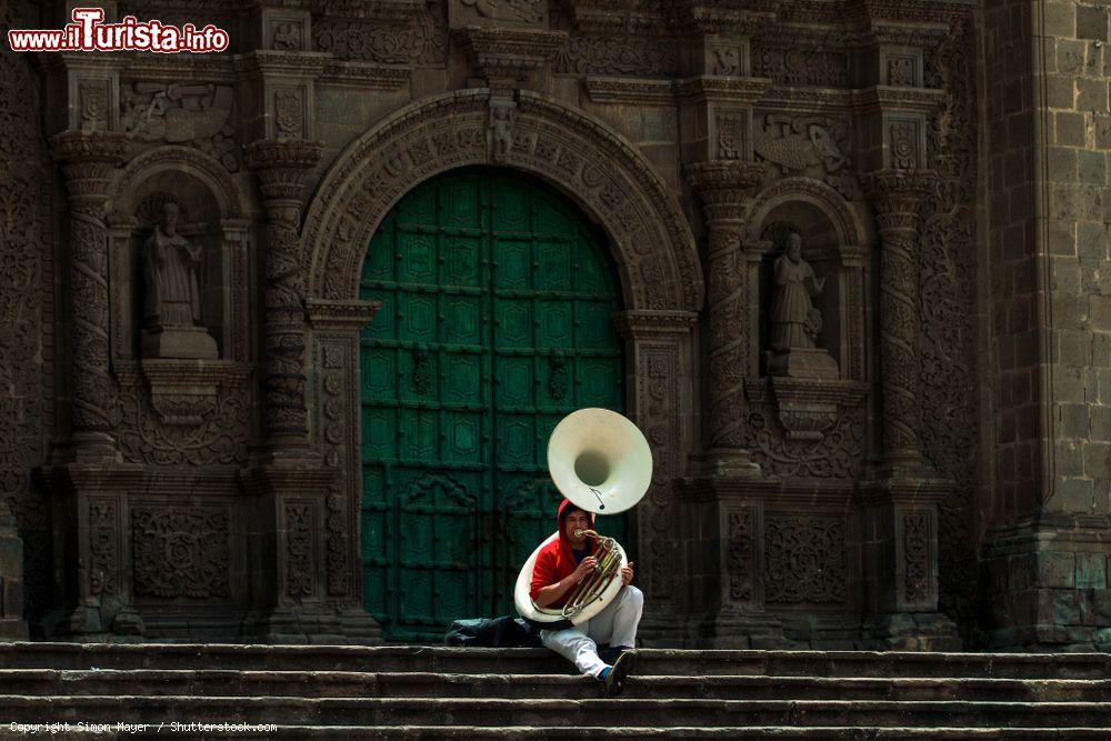 Immagine Un musicista seduto sui gradini della cattedrale di Puno suona il sousaphone (tuba) nel pomeriggio, Perù - © Simon Mayer / Shutterstock.com