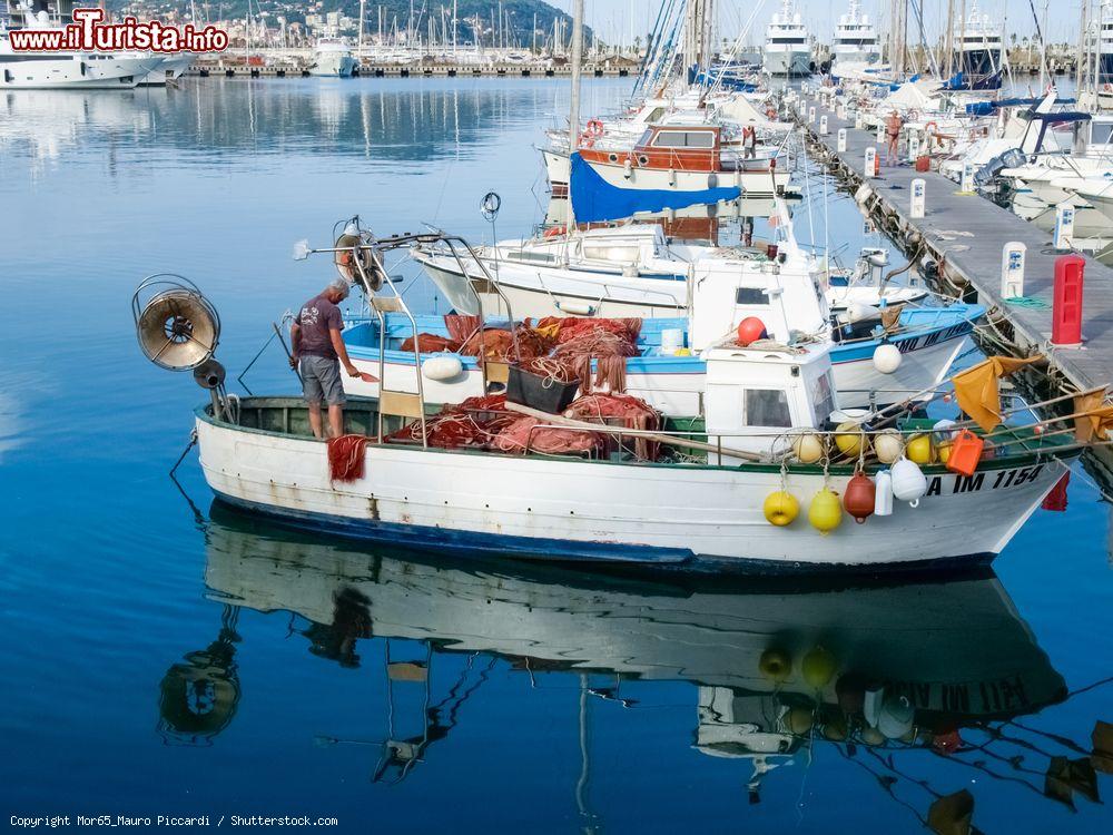 Immagine Un pescatore su una piccola barca in legno ormeggiata al porto di Oneglia, Imperia (Liguria) - © Mor65_Mauro Piccardi / Shutterstock.com