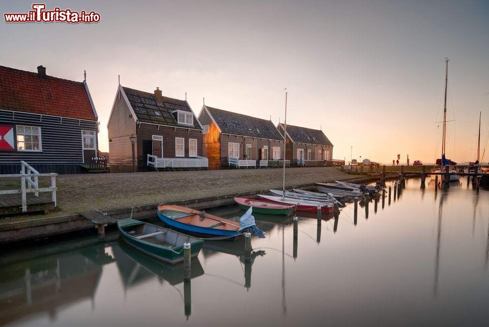 Immagine Un pittoresco scorcio del porto di un villaggio sull'isola di Marken, Olanda, al tramonto. Le graziose case in legno e le barche ormeggiate dei pescatori rendono autentica l'atmosfera di questo luogo che ha cambiato morfologia del terreno con il prosciugamento dei polder - © Pramio Garson / Shutterstock.com